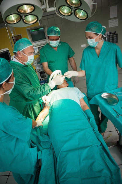 Photo chirurgien travaillant sur le bras d'un patient avec une équipe de chirurgiens