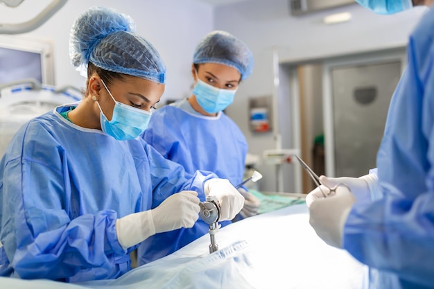 Chirurgienne concentrée effectuant une intervention chirurgicale avec son équipe dans la salle d'opération de l'hôpital Médecins pendant la chirurgie dans la salle d'opération