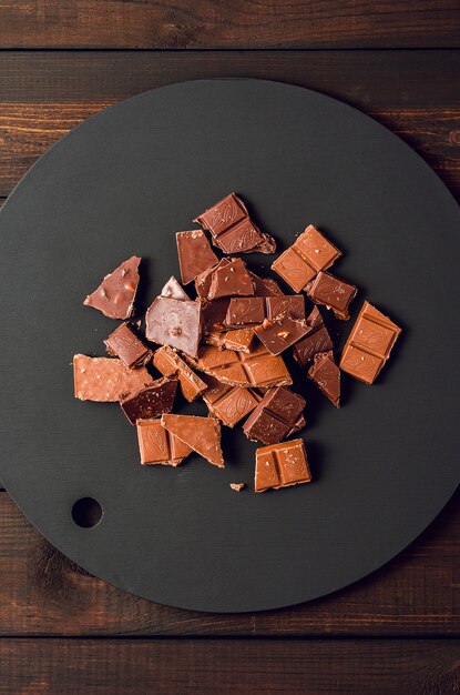 Chocolat au lait cassé sur un tableau noir sur un fond en bois marron.