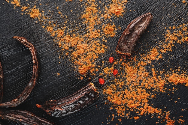 Chocolat de caroube et poudre de fruit de caroube sur une surface sombre