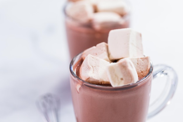 Chocolat chaud américain garni d'une grande guimauve dans une tasse en verre.