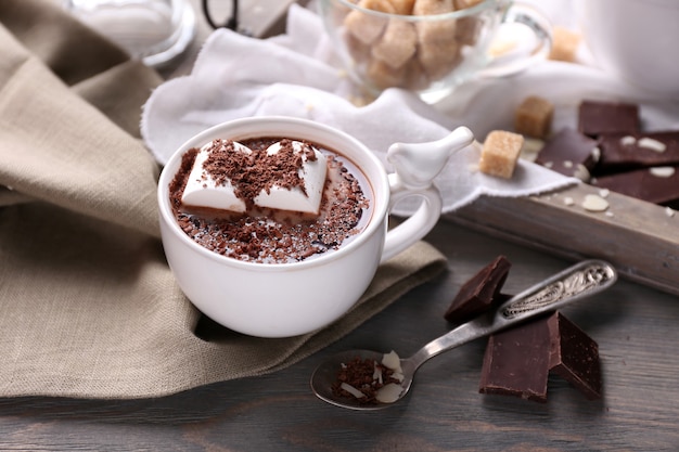Chocolat chaud aux guimauves en mug, sur plateau, sur fond de bois de couleur