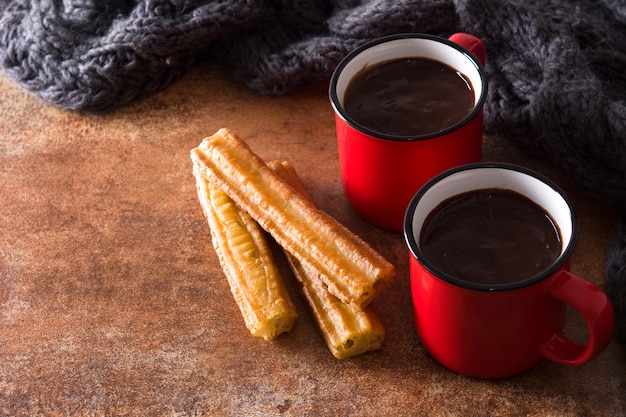 Chocolat chaud avec des churros sur une surface rouillée