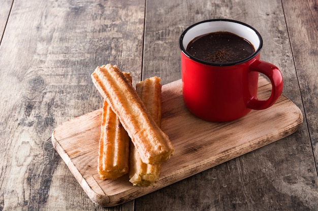 Chocolat chaud avec des churros sur une table en bois