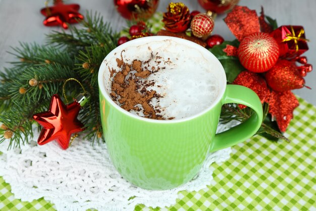 Chocolat chaud à la crème dans une tasse de couleur, sur une serviette, sur fond de décorations de Noël