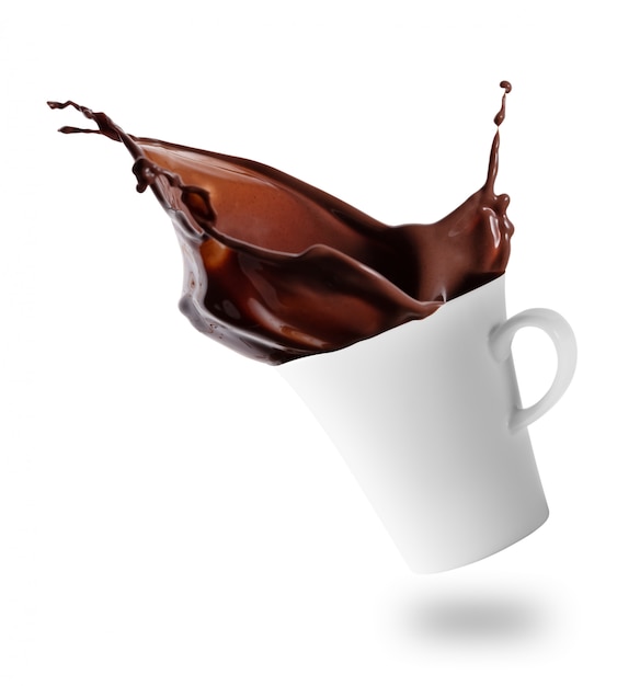 Le chocolat chaud éclabousse dans une tasse blanche inclinée