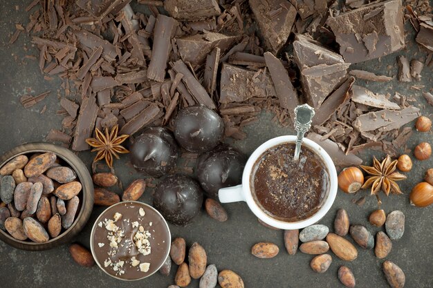 Chocolat chaud sur fond ancien dans une composition avec des fèves de cacao et des noix.