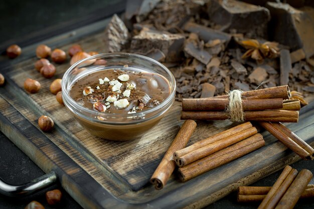Chocolat chaud sur fond ancien dans une composition avec des fèves de cacao et des noix.