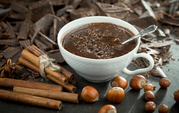 Chocolat chaud sur fond ancien dans une composition avec des fèves de cacao et des noix.