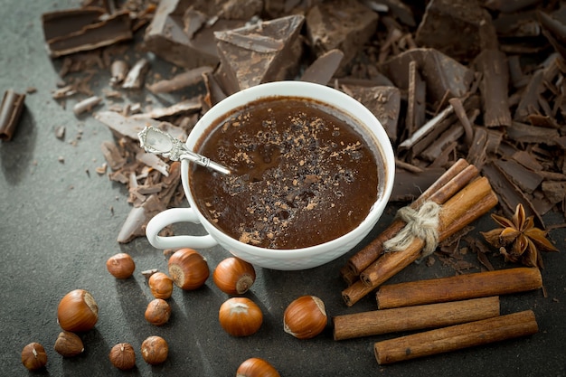 Chocolat chaud sur fond ancien dans une composition avec des fèves de cacao et des noix.