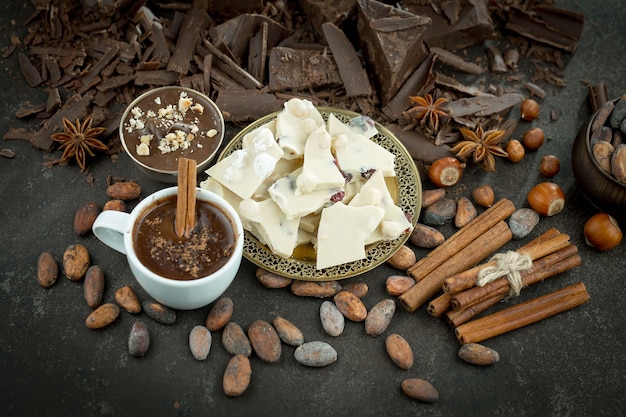 Chocolat chaud sur fond ancien dans une composition avec des fèves de cacao et des noix.