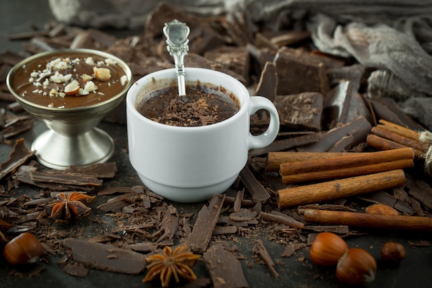 Chocolat chaud sur fond ancien dans une composition avec des fèves de cacao et des noix.