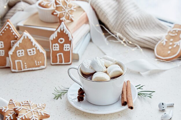 Chocolat chaud avec des guimauves et des biscuits de Noël faits maison en forme de maisons.