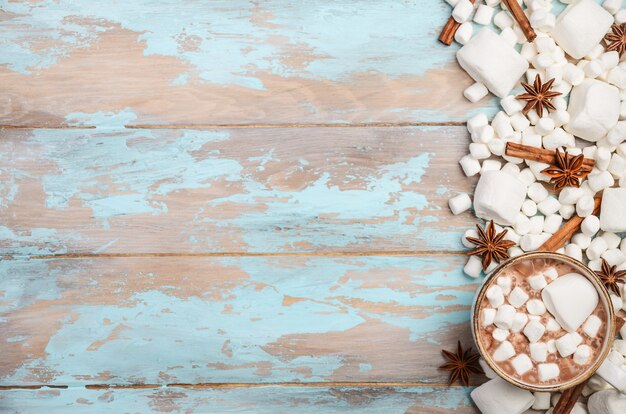 Chocolat chaud, guimauves blanches et épices d&#39;hiver sur fond en bois bleu