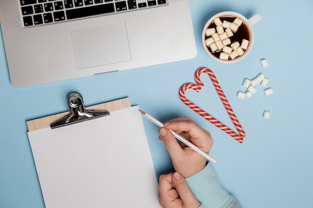 Chocolat chaud avec des guimauves et des bonbons pour ordinateur portable sur une vue de dessus de table bleue Mise à plat de Noël