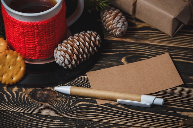 Chocolat chaud, pomme de pin, stylo, papier et biscuits