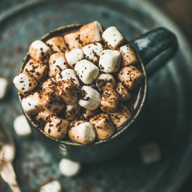 Chocolat chaud réchauffant l'hiver avec des guimauves dans une tasse carrée