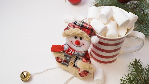 Chocolat chaud traditionnel avec des guimauves et des sucettes sur un fond texturé blanc