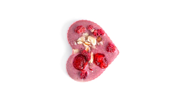 Chocolat cru en forme de coeur avec fruits secs et noix sur blanc