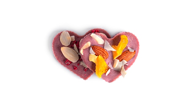 Chocolat cru en forme de coeur avec fruits secs et noix sur blanc