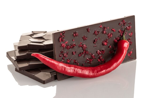 Chocolat cru noir au poivre et cerises lyophilisées sur fond blanc. Isolé