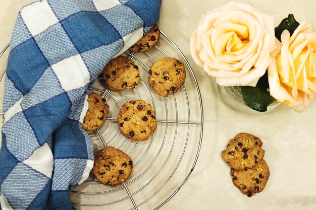 Chocolat fait maison Chip Cookies sur la grille avec serviette et de belles roses fleurs sur fond de marbre