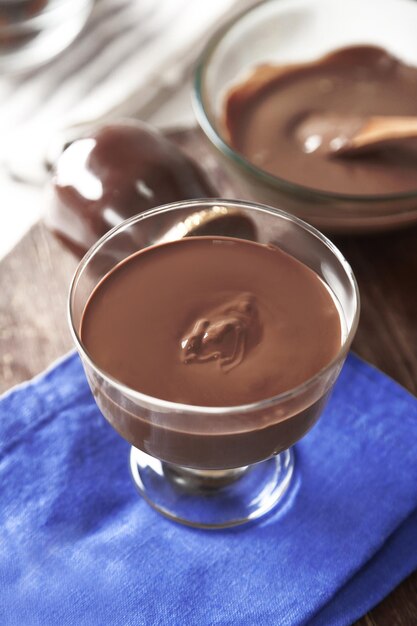 Chocolat fondu dans un bol en verre sur fond de bois