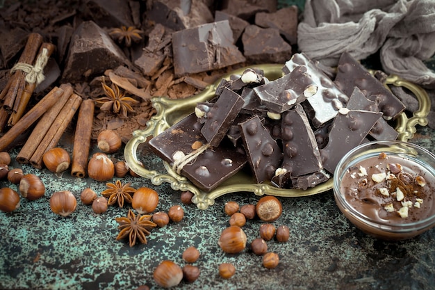 Chocolat noir dans une composition avec des fèves de cacao et des noix, sur un vieux fond.