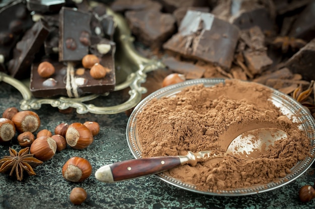 Chocolat noir dans une composition avec des fèves de cacao et des noix, sur un vieux fond.