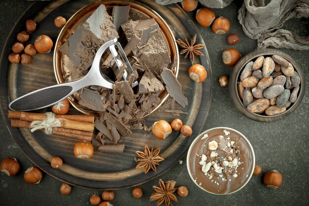 Chocolat noir dans une composition avec des fèves de cacao et des noix, sur un vieux fond.