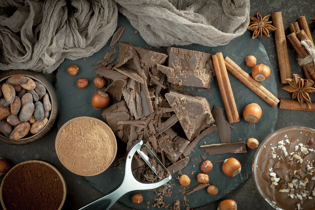 Photo chocolat noir dans une composition avec des fèves de cacao et des noix, sur un vieux fond.