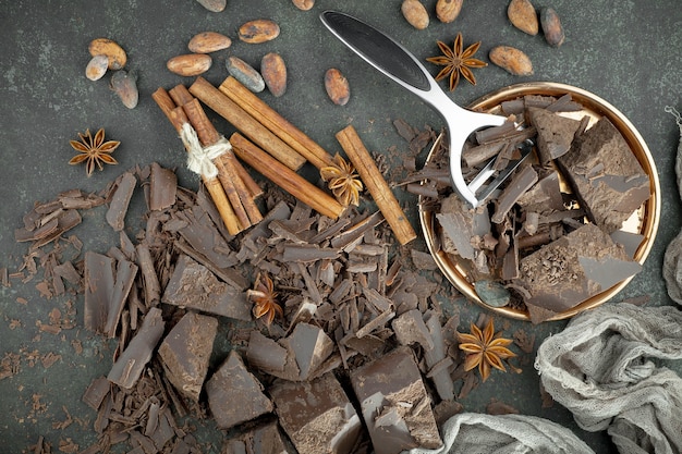 Photo chocolat noir dans une composition avec des fèves de cacao et des noix, sur un vieux fond.
