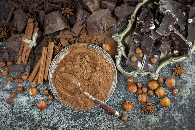 Chocolat noir dans une composition avec des fèves de cacao et des noix, sur un vieux fond.