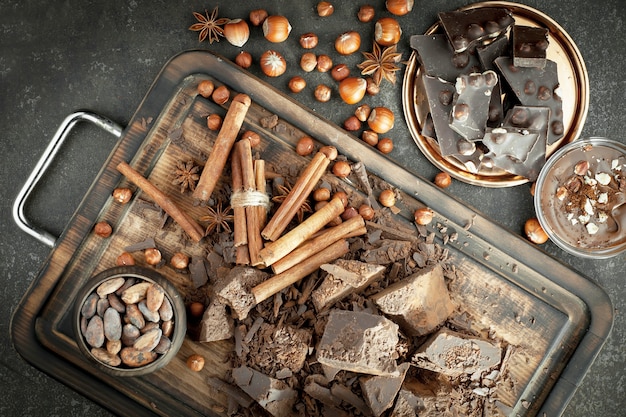 Chocolat noir dans une composition avec des fèves de cacao et des noix, sur un vieux fond.