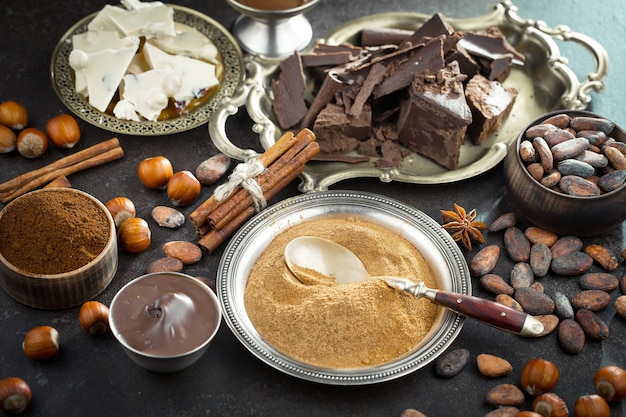 Chocolat noir dans une composition avec des fèves de cacao et des noix, sur un vieux fond.