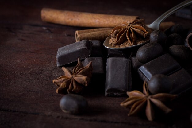 Chocolat noir, épices, cuillère à thé sur une surface en bois