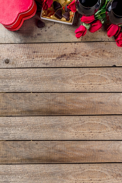 Chocolat, roses, verres à vin et boîte coeur sur table en bois