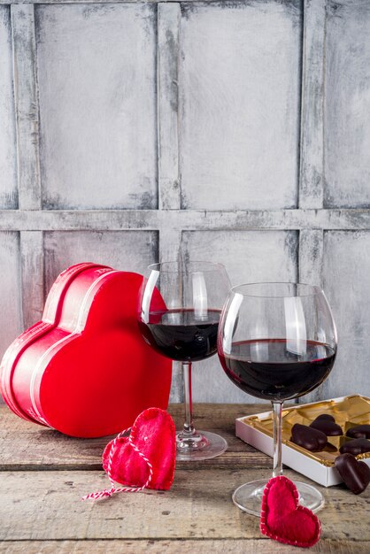 Chocolat, roses, verres à vin et boîte coeur sur table en bois