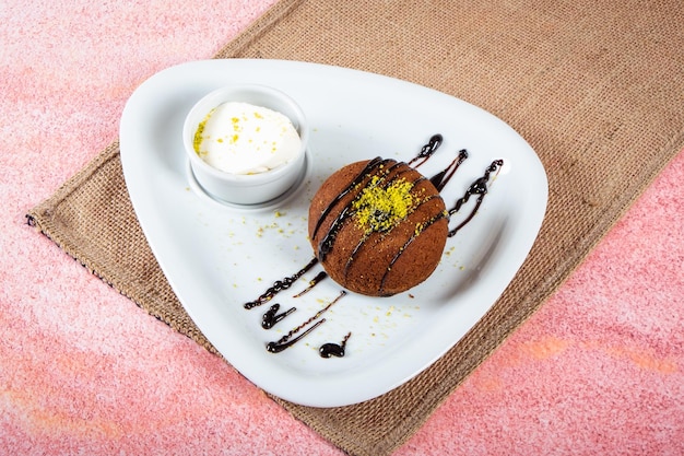 Chocolat soufflé à la pistache avec glace sur plaque blanche fond rose et osier