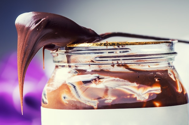 Chocolat à tartiner en cuillère. Un pot de pâte à tartiner au chocolat aux noisettes.