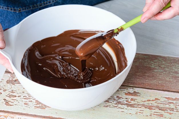 Chocolat tempérant confiseur avec une spatule dans un bol blanc.