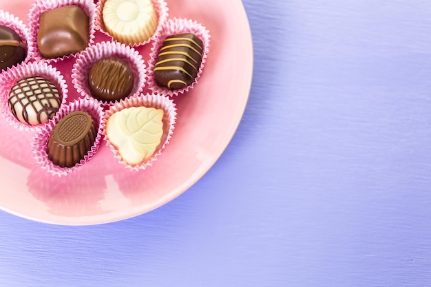 Chocolats assortis sur plaque rose.