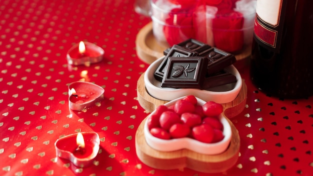 Chocolats et bonbons sur des assiettes en forme de coeur. Table de fête pour rendez-vous amoureux. Fond rouge