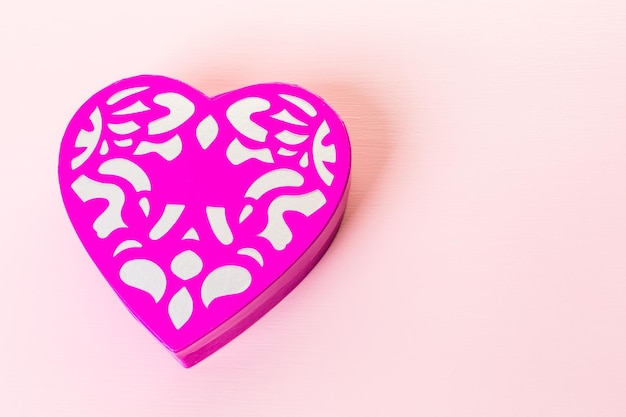 Chocolats dans une boîte en forme de coeur sur fond rose.