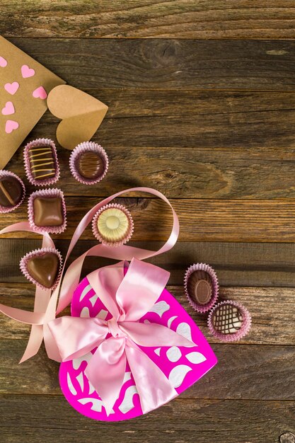 Photo chocolats dans une boîte en forme de coeur sur une table en bois rustique.