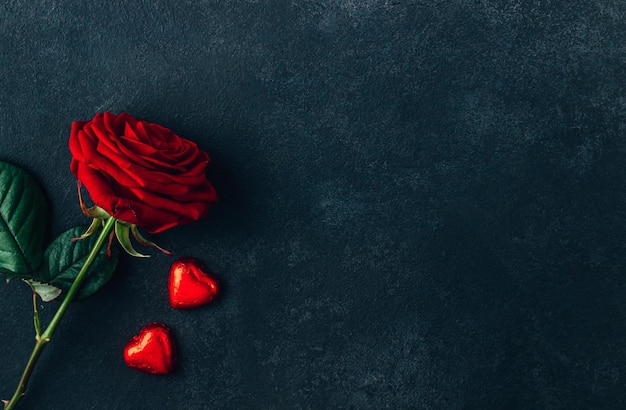 Chocolats en forme de coeur et rose rouge sur fond noir