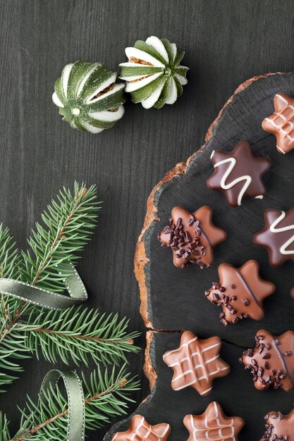 Chocolats en forme d'étoile sur un mur texturé foncé avec des brindilles d'arbre de Noël