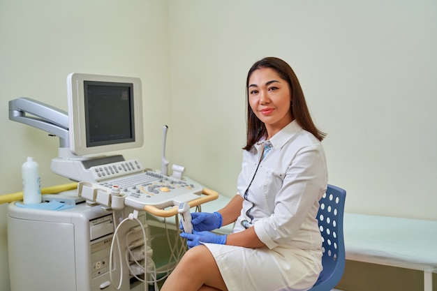 Échographie asiatique femme médecin dans une blouse blanche à côté de la machine à ultrasons.