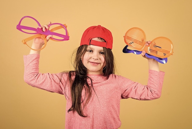 Choisir des lunettes à la mode parfaites pour son style Fêtarde cool choisissant des lunettes de fantaisie Petit enfant élégant avec des lunettes de mode Mignon petit enfant tenant des lunettes de fête