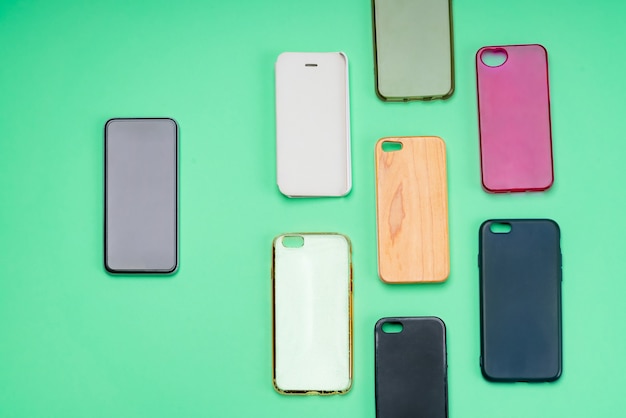 Choix de coques arrières en plastique multicolores pour téléphones portables sur fond vert avec un smartphone sur le côté